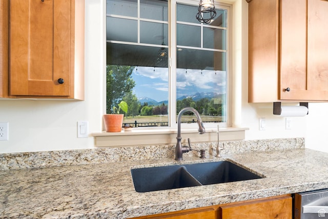 kitchen featuring dishwasher, light stone countertops, and sink