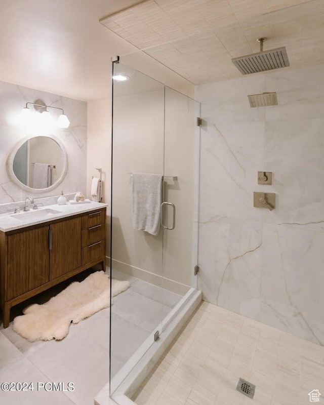 bathroom with a shower with door, vanity, and tile patterned floors