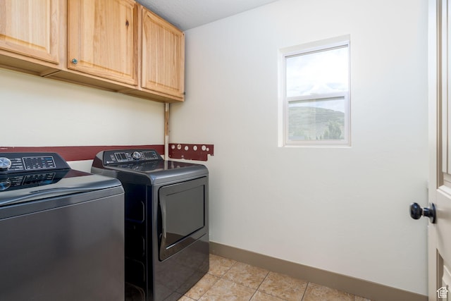 washroom with washer and dryer, light tile patterned floors, and cabinets