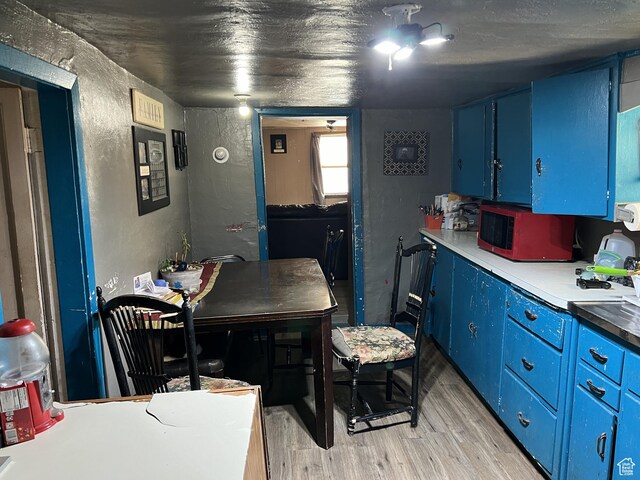 736 E Hatchery Rd, Bicknell, UT 84715 - kitchen featuring light wood-style floors, blue cabinetry, and a textured wall