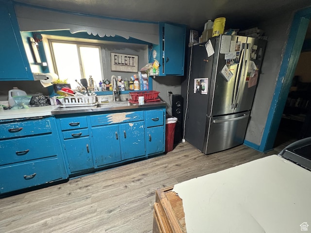 736 E Hatchery Rd, Bicknell, UT 84715 - kitchen featuring light wood finished floors, a sink, freestanding refrigerator, and blue cabinetry