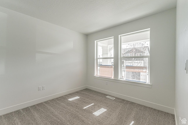 carpeted empty room featuring a textured ceiling