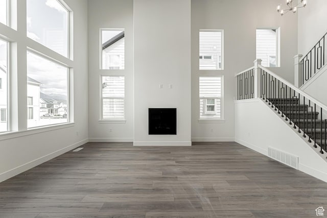 unfurnished living room with dark hardwood / wood-style flooring, a high ceiling, and an inviting chandelier