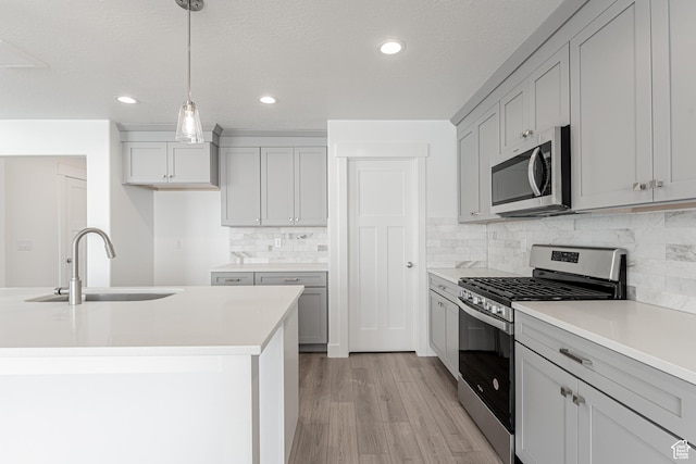 kitchen with pendant lighting, sink, gray cabinets, tasteful backsplash, and stainless steel appliances