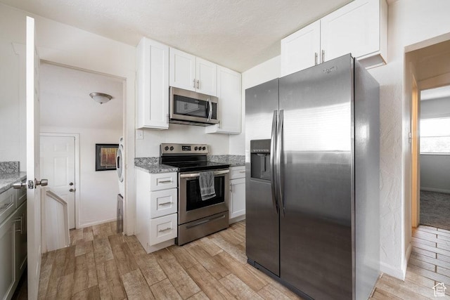 6 Park Ave, Tooele, UT 84074 - kitchen featuring appliances with stainless steel finishes, light wood-style floors, white cabinetry, and light stone countertops