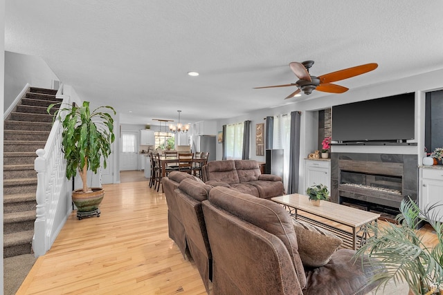 living room featuring stairway, a tile fireplace, a textured ceiling, and light wood-style floors