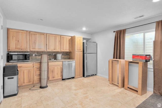 kitchen featuring tasteful backsplash, visible vents, light brown cabinetry, light countertops, and stainless steel appliances