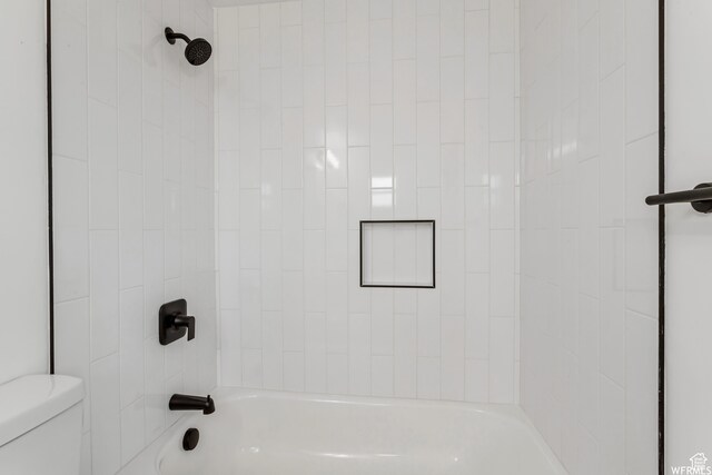bathroom with tiled shower / bath combo and toilet