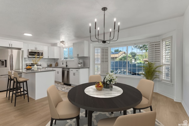 dining room with light hardwood / wood-style floors, sink, and an inviting chandelier