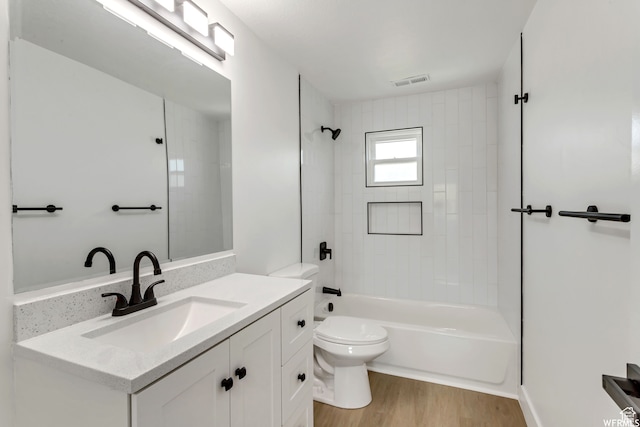 full bathroom with vanity, tiled shower / bath combo, toilet, and hardwood / wood-style floors