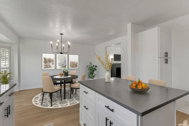 kitchen with a notable chandelier, light hardwood / wood-style flooring, white cabinets, and a kitchen island