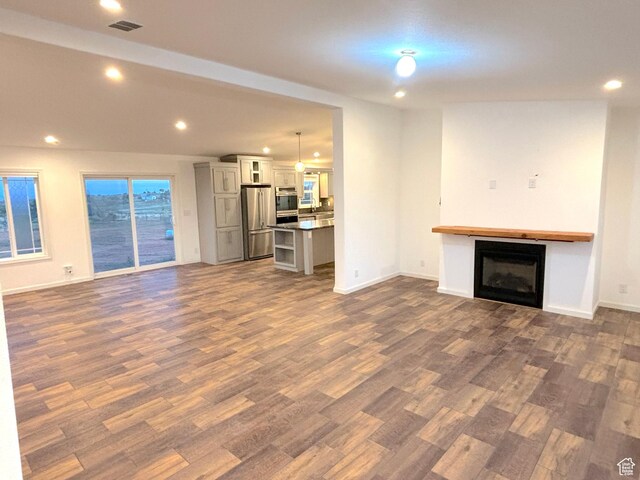 944 E Kiva Dr, Blanding, UT 84511 - unfurnished living room with baseboards, dark wood-type flooring, a glass covered fireplace, and recessed lighting