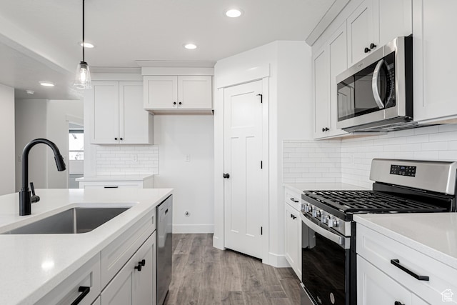 kitchen featuring sink, light hardwood / wood-style flooring, hanging light fixtures, appliances with stainless steel finishes, and white cabinets