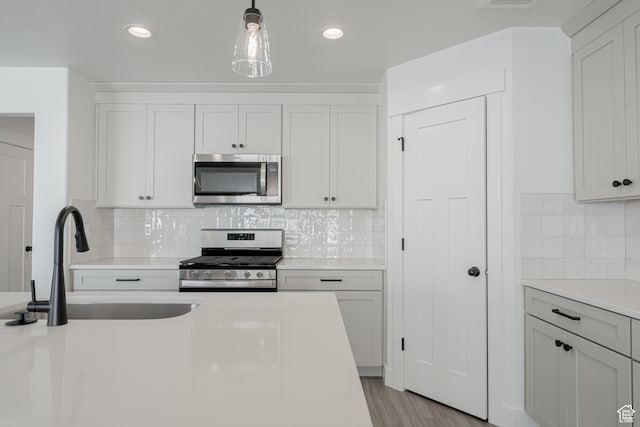 kitchen with pendant lighting, light wood-type flooring, white cabinetry, and stainless steel appliances