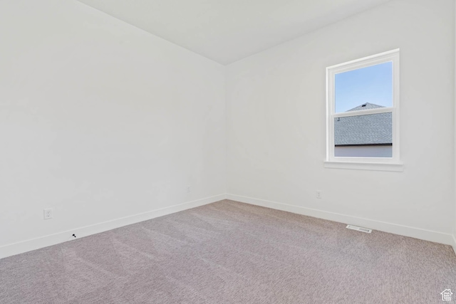 spare room with carpet, visible vents, and baseboards