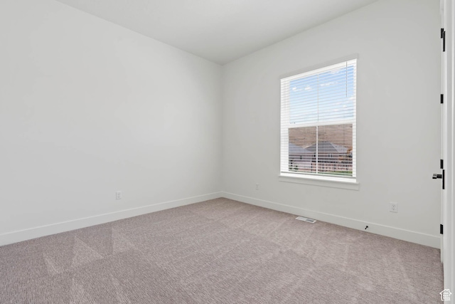 empty room with light colored carpet, baseboards, and visible vents
