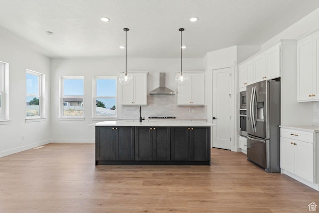 kitchen with stainless steel fridge with ice dispenser, wall chimney range hood, light countertops, and white cabinets