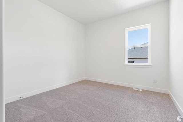 spare room featuring visible vents, baseboards, and light colored carpet