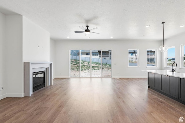 unfurnished living room with baseboards, a ceiling fan, and a wealth of natural light