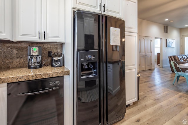 kitchen with tasteful backsplash, white cabinets, light hardwood / wood-style floors, and black appliances