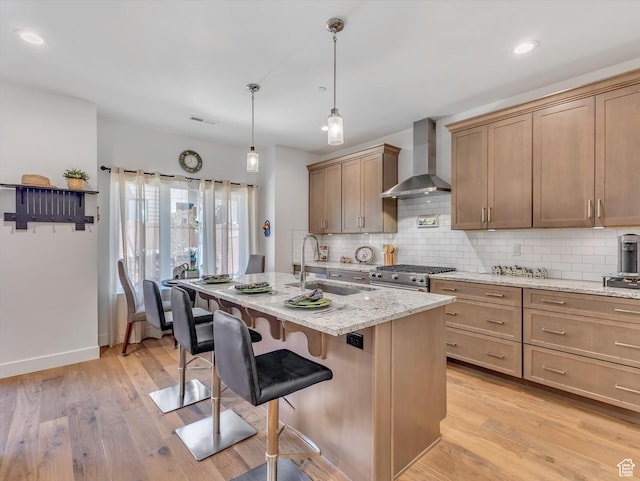 8257 N Sandalwood Ln, Park City, UT 84098 - kitchen with a kitchen island with sink, sink, wall chimney exhaust hood, light stone counters, and a kitchen bar