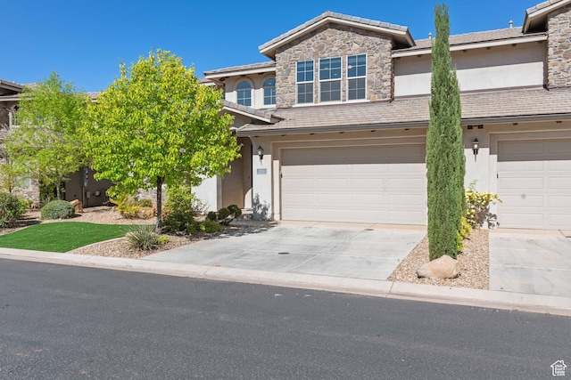 view of front of home with an attached garage, stone siding, concrete driveway, and stucco siding