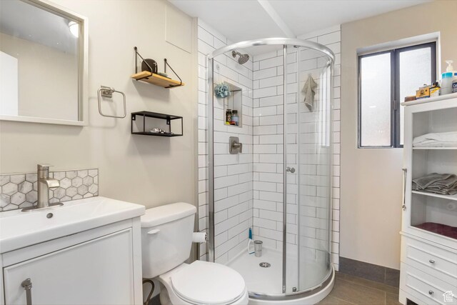 bathroom featuring tile patterned flooring, vanity, a shower with shower door, and toilet