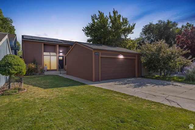 view of front of property featuring solar panels, a garage, and a front yard