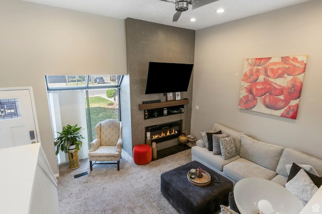 carpeted living room with ceiling fan and a fireplace