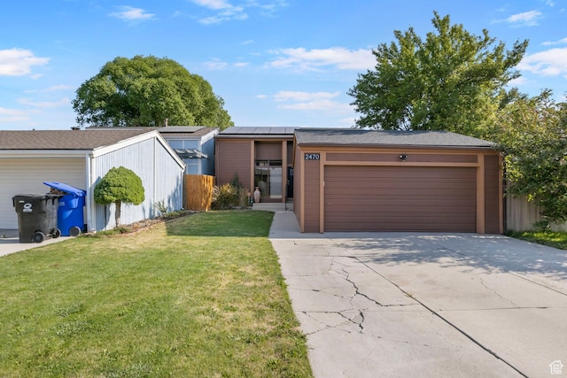 ranch-style home with solar panels, a garage, and a front lawn