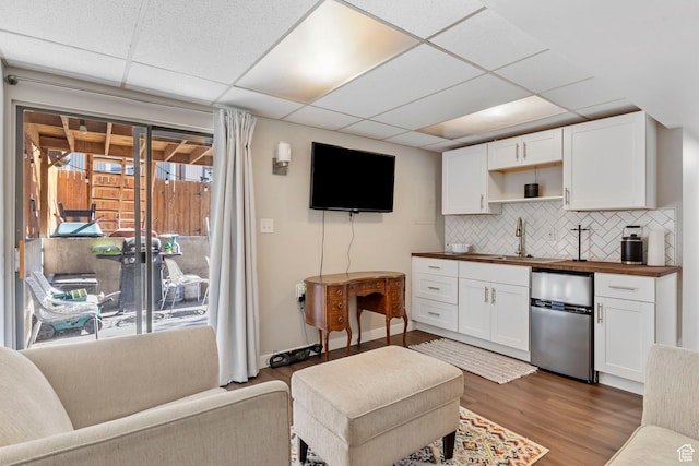 kitchen with a paneled ceiling, white cabinetry, and fridge