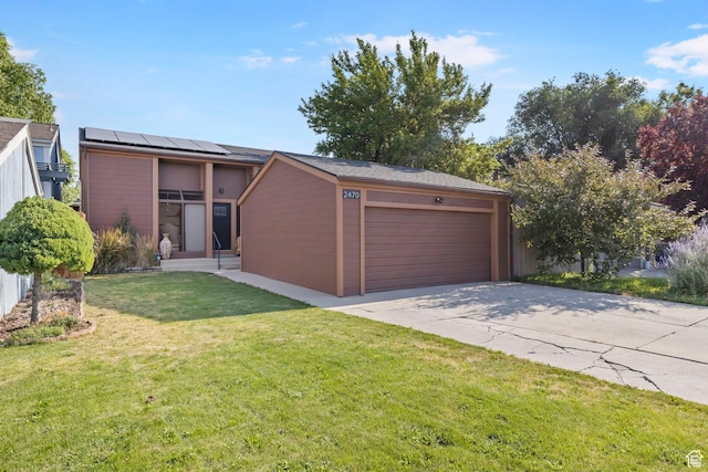 view of front of property with a front lawn, a garage, and solar panels