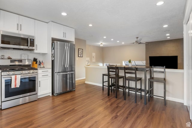 kitchen with white cabinets, dark hardwood / wood-style floors, ceiling fan, and stainless steel appliances