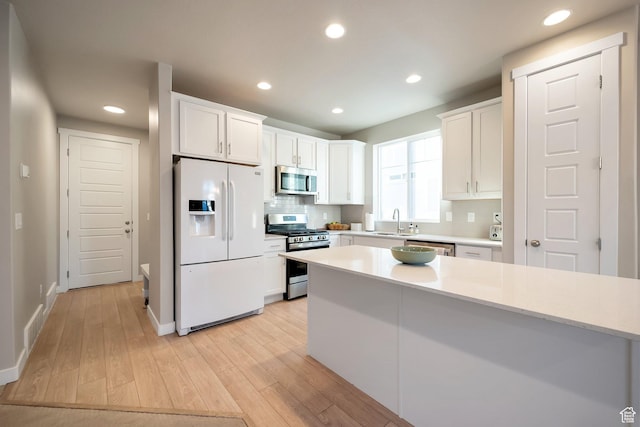 6618 N Furner Rdg, Eagle Mountain, UT 84005 - kitchen featuring sink, stainless steel appliances, light hardwood / wood-style floors, decorative backsplash, and white cabinets