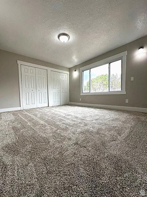 3715 W 11500 N, Neola, UT 84053 - unfurnished bedroom featuring multiple closets, a textured ceiling, and carpet flooring