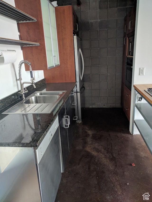 kitchen featuring dark stone countertops, appliances with stainless steel finishes, and sink
