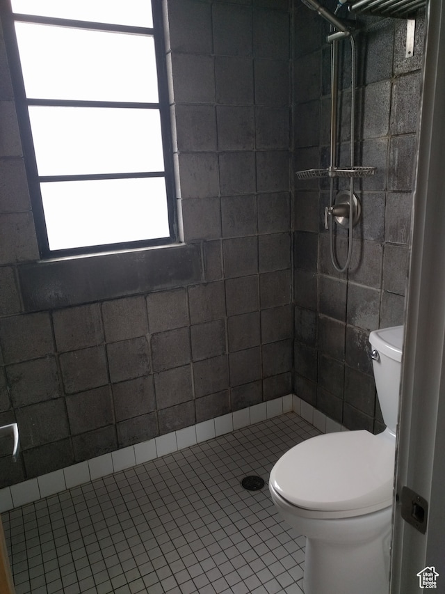bathroom featuring tile patterned flooring, toilet, and a tile shower