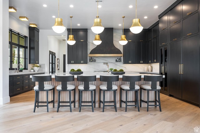 3905 S Quarry Ridge Dr, St George, UT 84790 - kitchen featuring decorative light fixtures, custom exhaust hood, light hardwood / wood-style floors, and a large island with sink