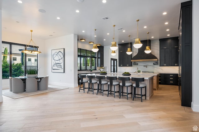 3905 S Quarry Ridge Dr, St George, UT 84790 - kitchen with a breakfast bar, tasteful backsplash, a large island with sink, custom exhaust hood, and hanging light fixtures