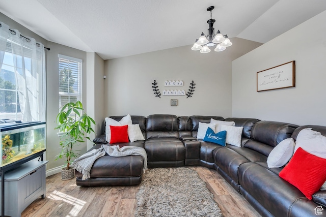 living room featuring lofted ceiling, a notable chandelier, and light hardwood / wood-style floors