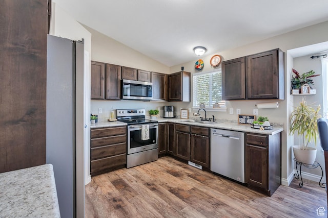 kitchen with dark brown cabinetry, sink, vaulted ceiling, and appliances with stainless steel finishes