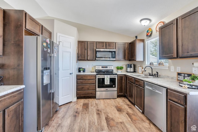 kitchen with lofted ceiling, sink, dark brown cabinetry, stainless steel appliances, and light hardwood / wood-style flooring