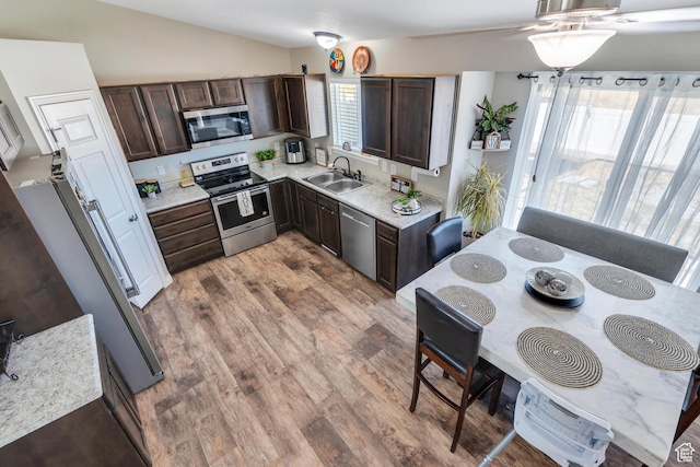 kitchen featuring sink, appliances with stainless steel finishes, hardwood / wood-style floors, dark brown cabinets, and vaulted ceiling