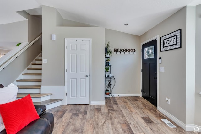 entryway with wood-type flooring and lofted ceiling