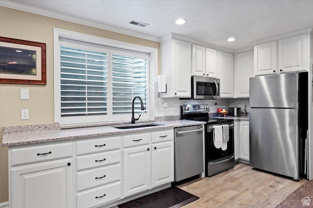 kitchen featuring light wood-type flooring, visible vents, a sink, stainless steel appliances, and white cabinets