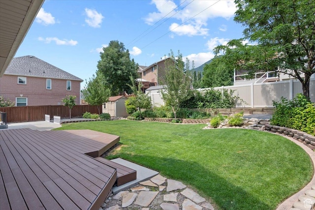 view of yard with a deck, an outbuilding, a storage unit, and a fenced backyard
