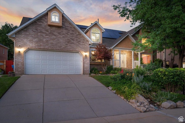 view of front of house featuring a garage, roof mounted solar panels, brick siding, and driveway