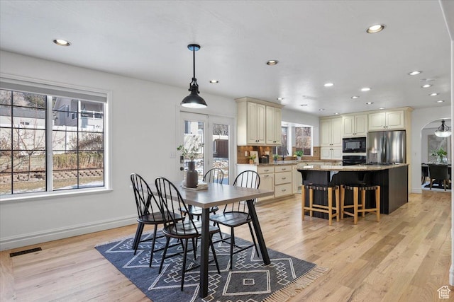 dining space featuring visible vents, recessed lighting, arched walkways, light wood-style floors, and baseboards