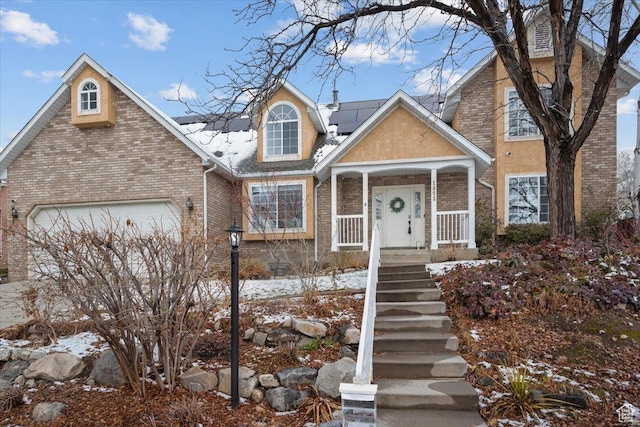 view of front of house with an attached garage, brick siding, and roof mounted solar panels