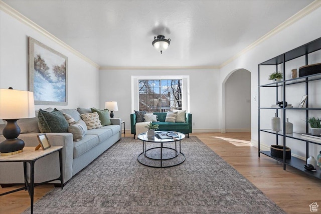 living room featuring baseboards, arched walkways, wood finished floors, and ornamental molding